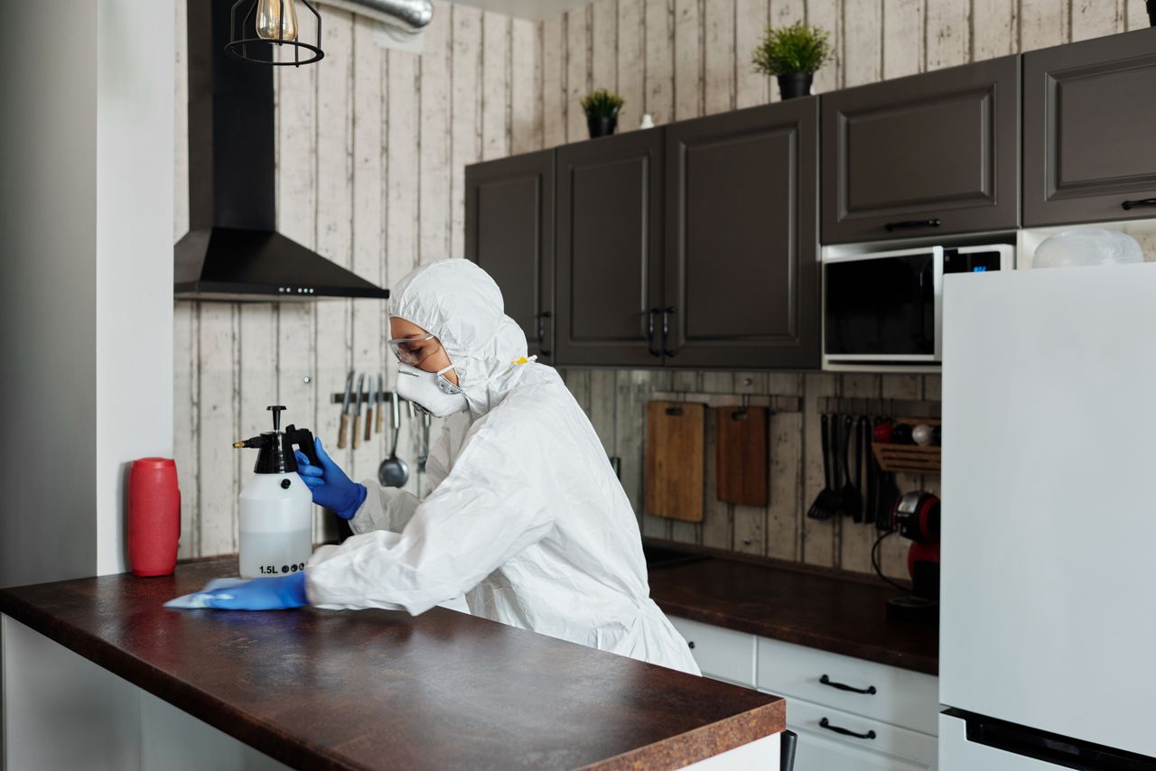 why-choose-us A worker in protective gear disinfects a kitchen, ensuring a clean and safe environment.